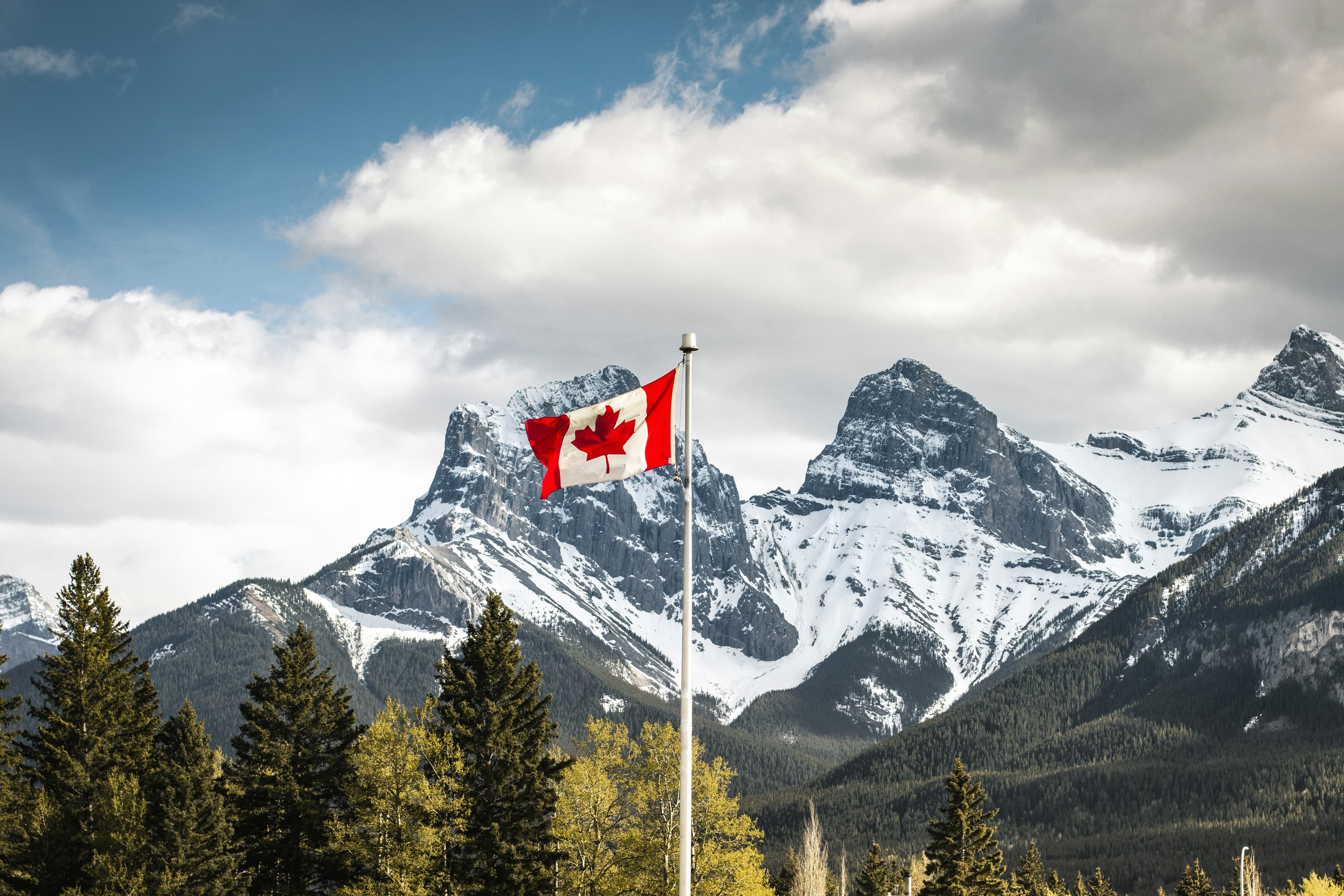 The Canadian flag over mountains and trees